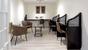 Un interior moderno con una zona de estar, una mesa con un florero y dos obras de arte enmarcadas en la pared.