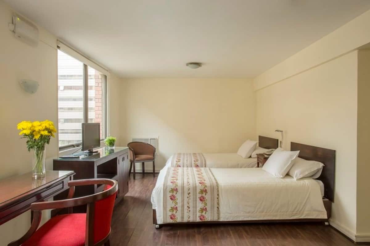 A hotel room with a bed, desk, chair, and a window with a view.