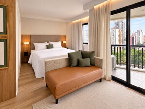 A hotel room with a bed, a sofa, a view of the city, and a balcony. - Estanplaza Ibirapuera (São Paulo)