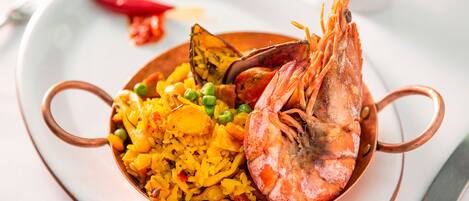 A bowl of rice with peas and shrimp on a plate.