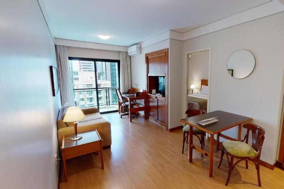 Habitación de hotel con comedor, sofá, mesa y un amplio ventanal.