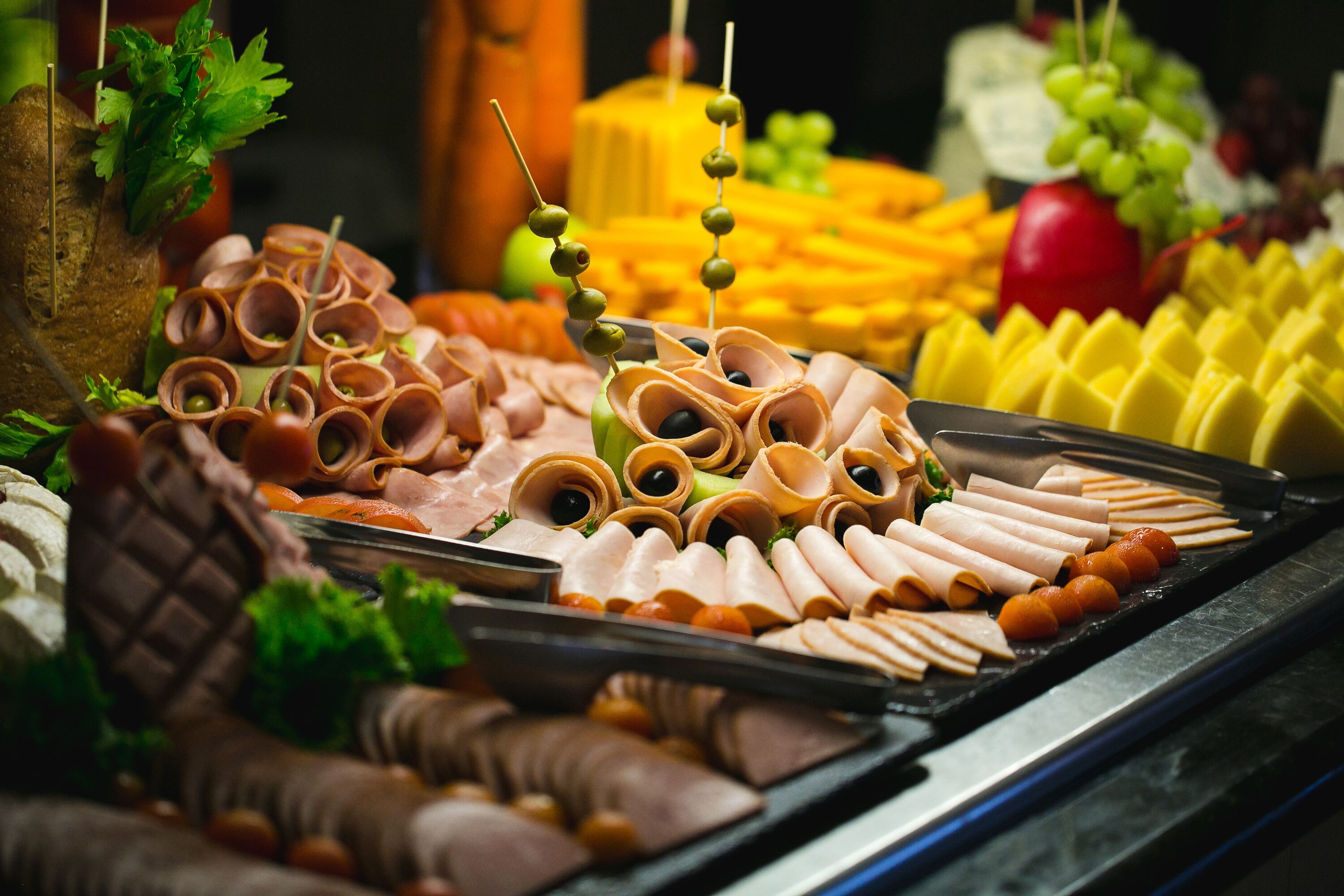 A charcuterie board with various meats, cheeses, and garnishes.