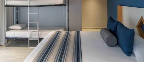 A bunk bed with a ladder, a single bed with pillows, and a wooden headboard.