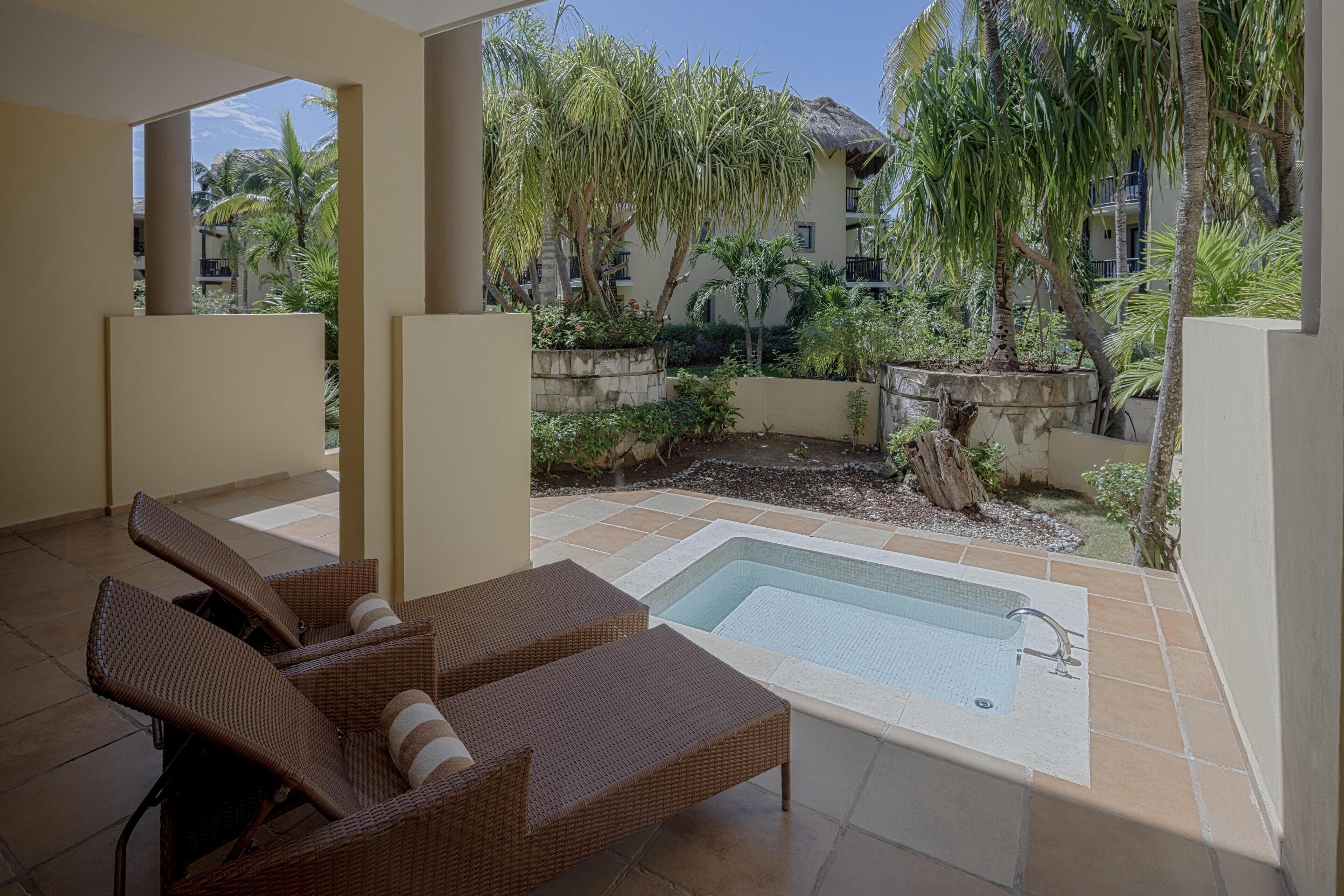 A poolside area with lounge chairs, a swimming pool, and surrounding greenery.