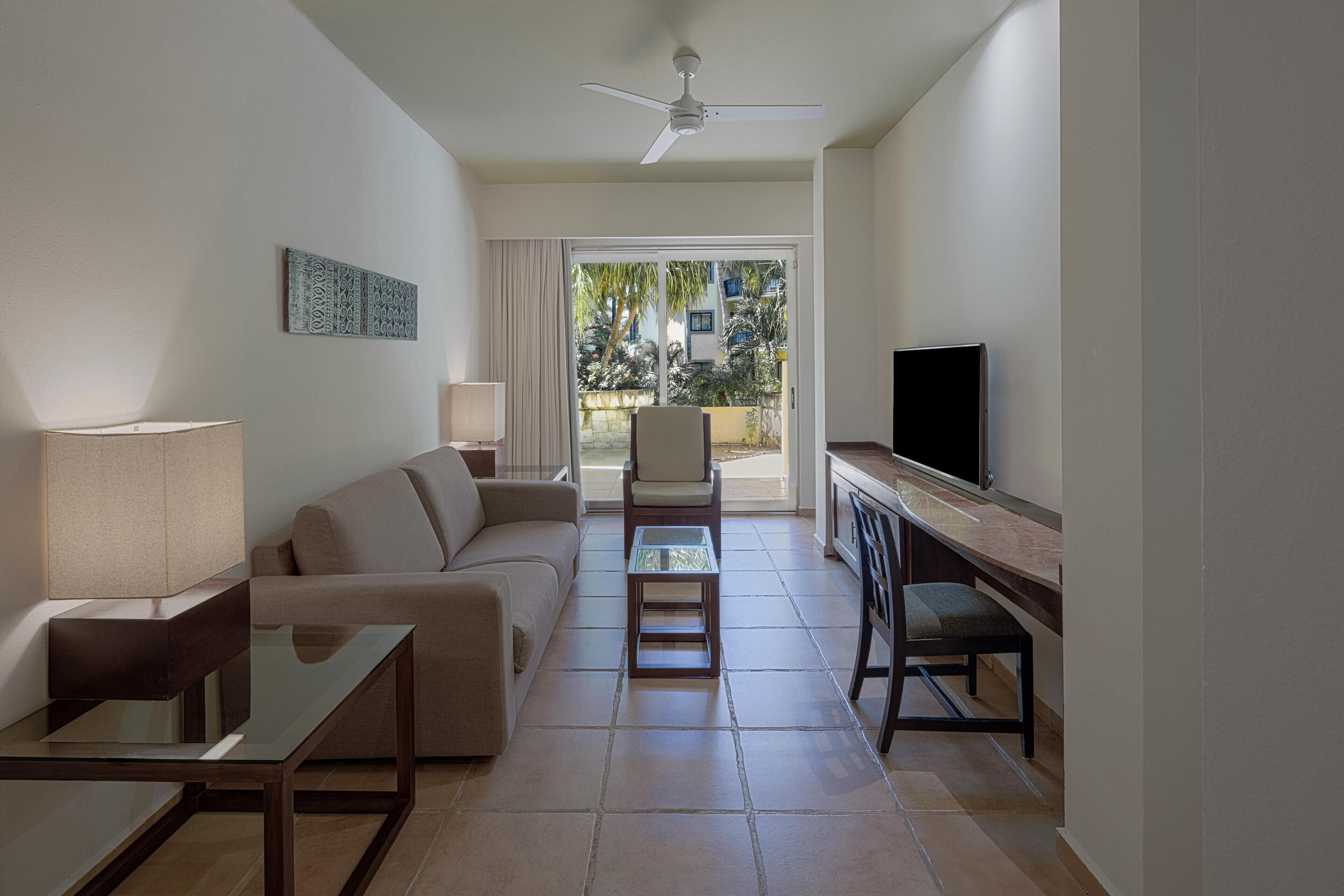 A modern living room with a sofa, coffee table, TV, and a balcony with a view.