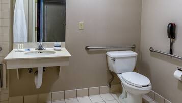 A bathroom with a sink, mirror, toilet, and hand dryer.