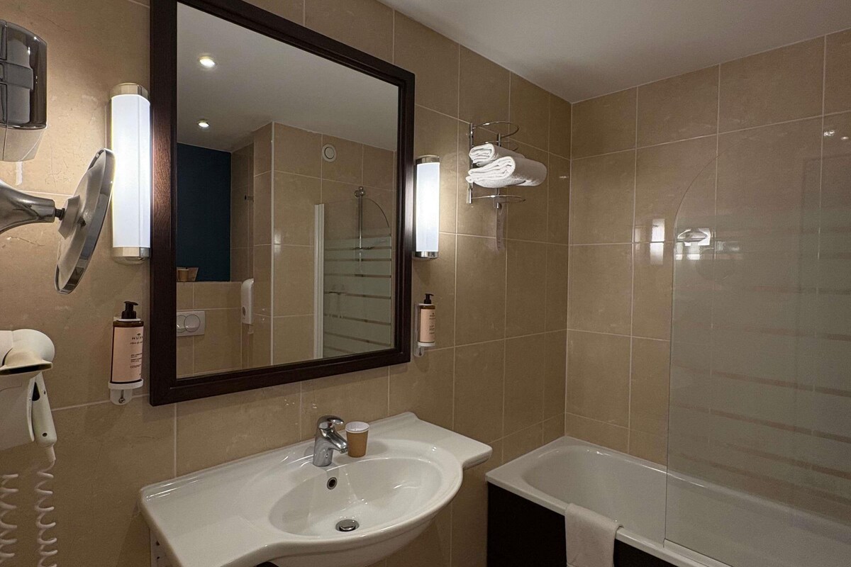 Un bagno con lavandino, specchio, porta asciugamani e vasca da bagno.