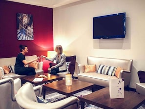 Una habitación con dos sofás, una mesa de centro, un televisor y un cuadro en la pared.