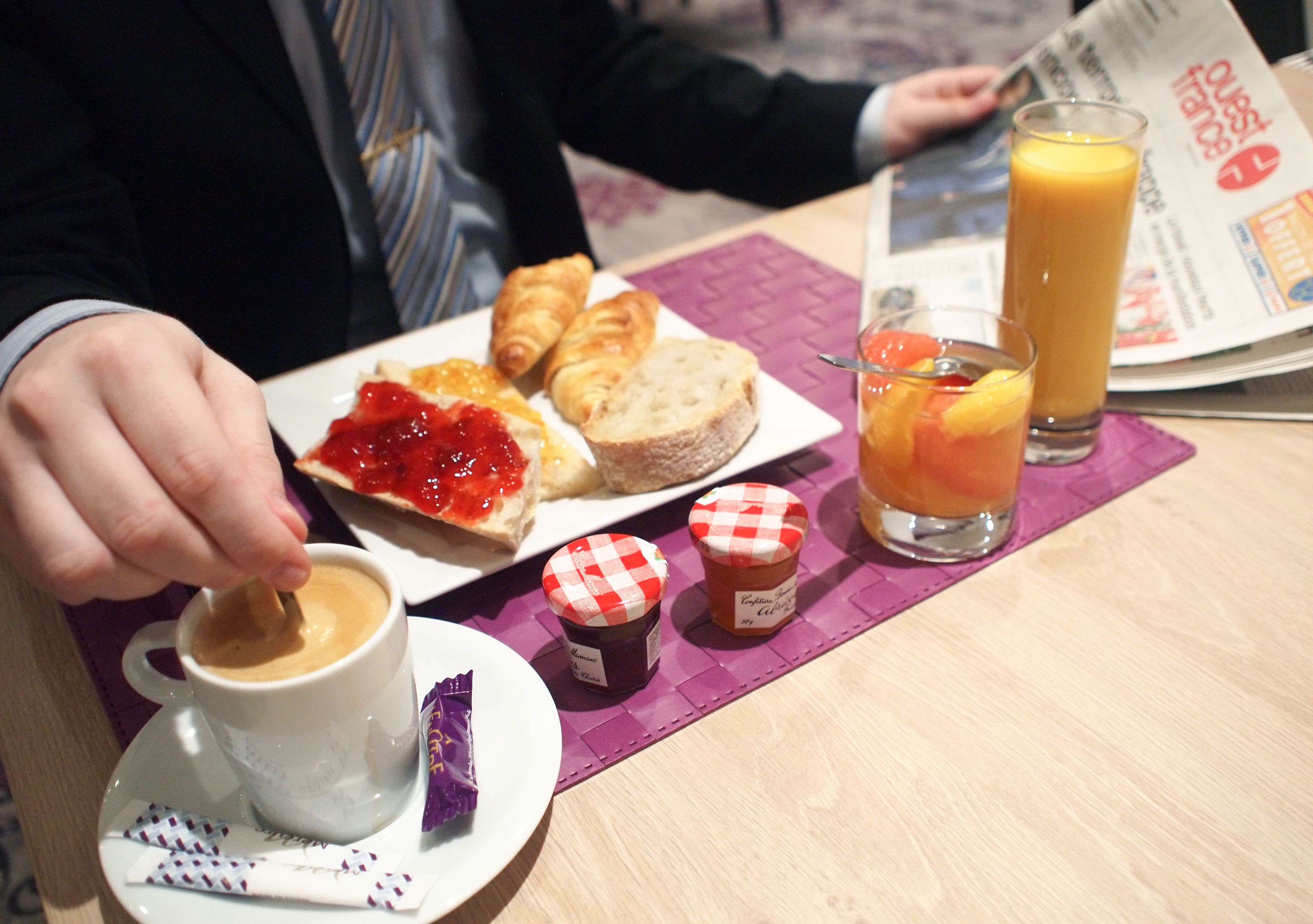 Ein Frühstückstisch mit Croissants, Marmelade, einem Glas Orangensaft und einer Kaffeetasse.