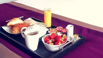 Frühstückswagen mit Croissants, Orangensaft im Glas, Erdbeeren in einer Schüssel, einer Kaffeekanne und Gewürzen.