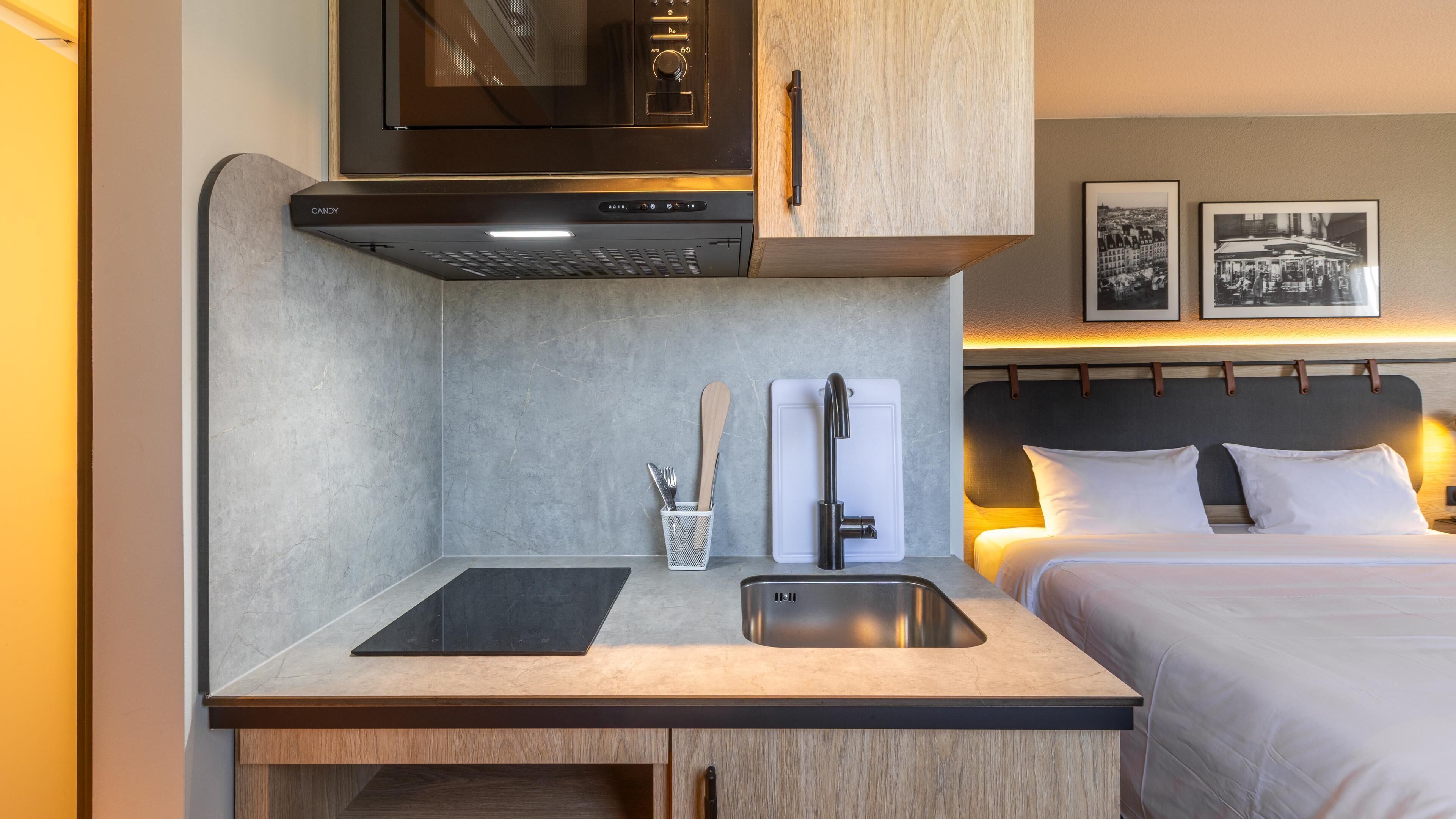 A compact kitchenette with a microwave, sink, and storage cabinets.