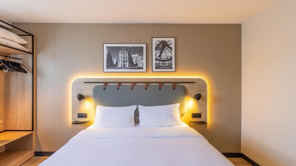 A hotel room with a bed, bedside lamps, a headboard, a wardrobe, and two framed pictures on the wall. - Campanile PRIME - Le Blanc Mesnil (Le Blanc-Mesnil)