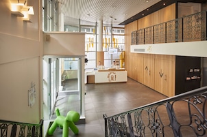A modern hotel lobby with a reception desk, a staircase, and a view of the interior.