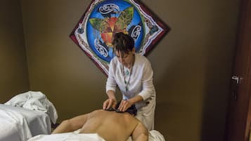 Guests can enjoy a rejuvenating massage in this serene space, complete with a comfortable bed and a beautiful piece of artwork.