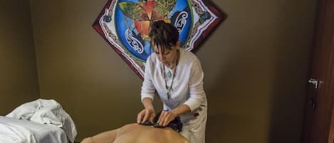 A massage therapy session in a room with a bed and a decorative wall piece.