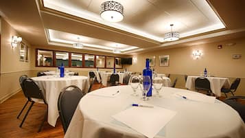 A conference room with round tables, chairs, and tables set with blue bottles and glasses.