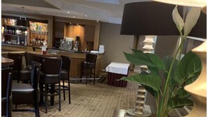 Eine Hotelhalle mit Barbereich, Sitzgelegenheiten und einer Zierpflanze.