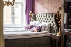 Classic bedroom with a large bed, tufted headboard, and decorative mirror.
