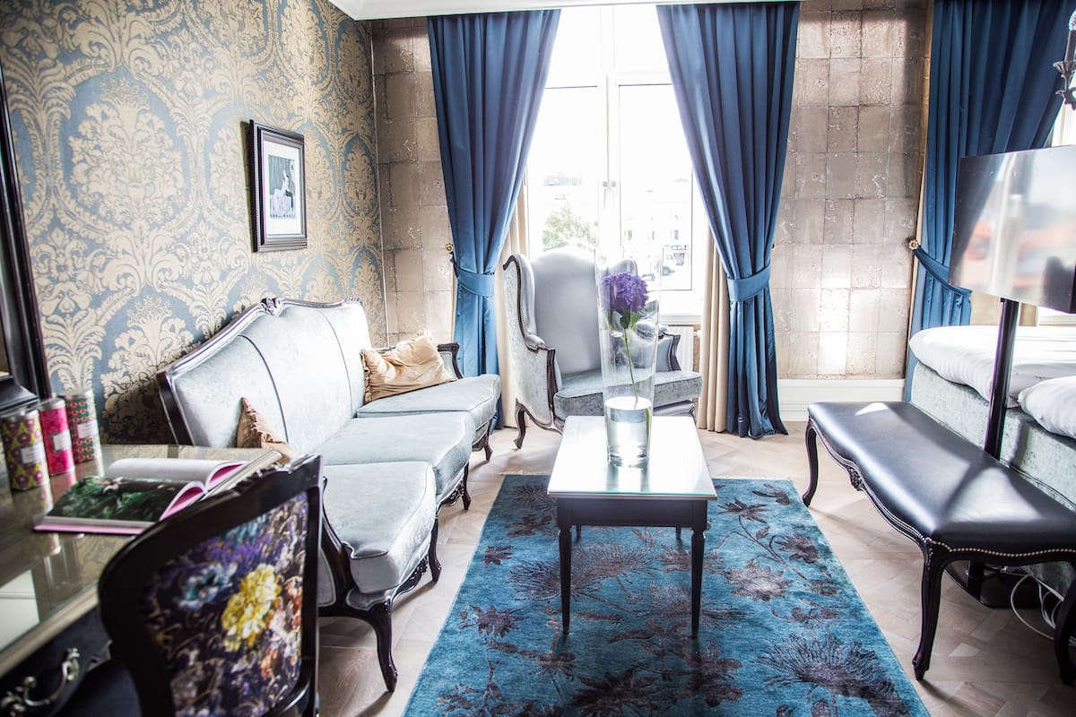 A living room with a sofa, armchairs, a coffee table, and a rug.