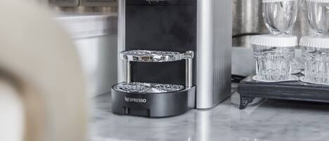 Una máquina de café Nespresso con depósito de agua, bandeja de goteo y dos dispensadores de café.