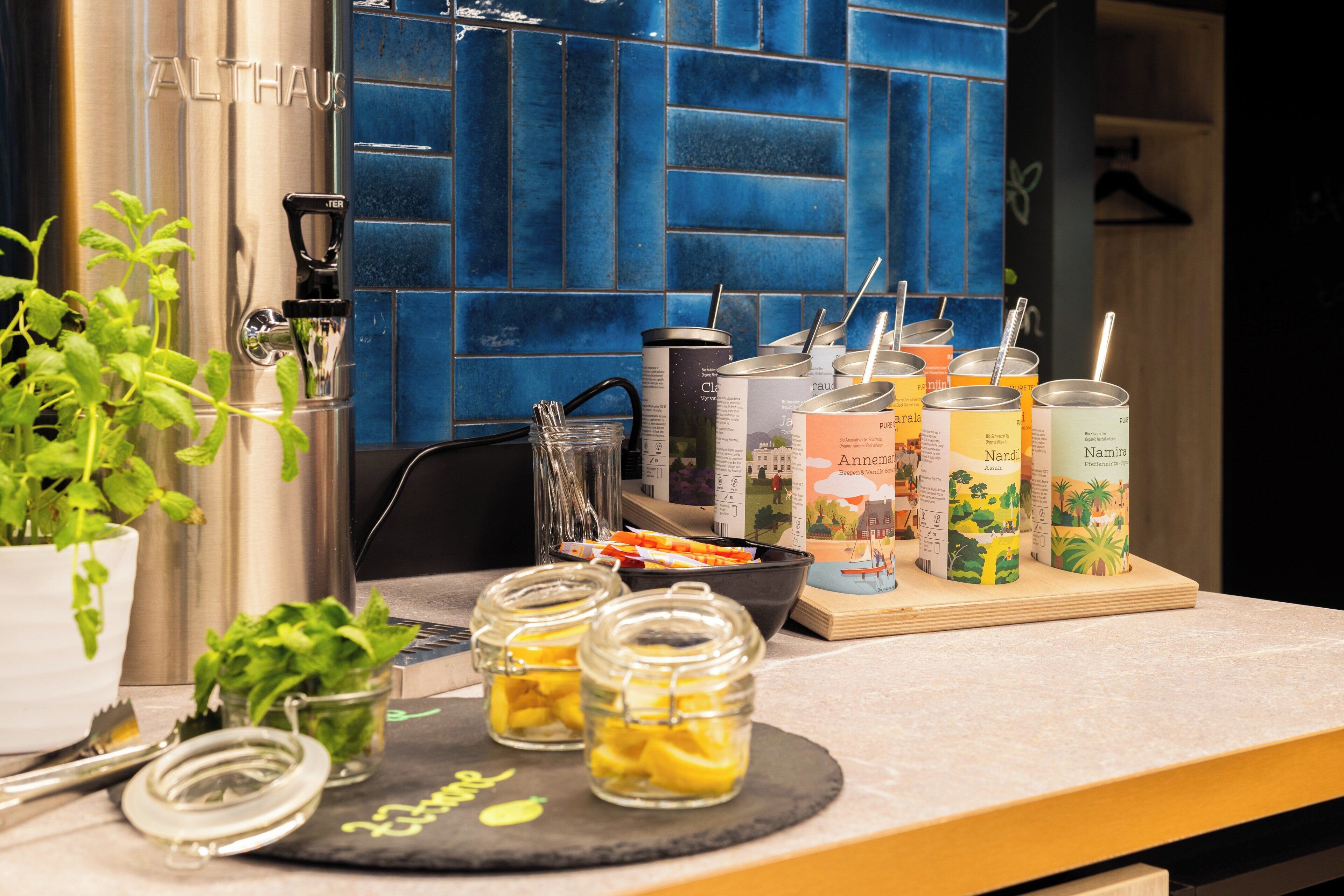 A kitchen counter with a coffee machine, jars of preserved lemons, and a variety of coffee and tea containers.
