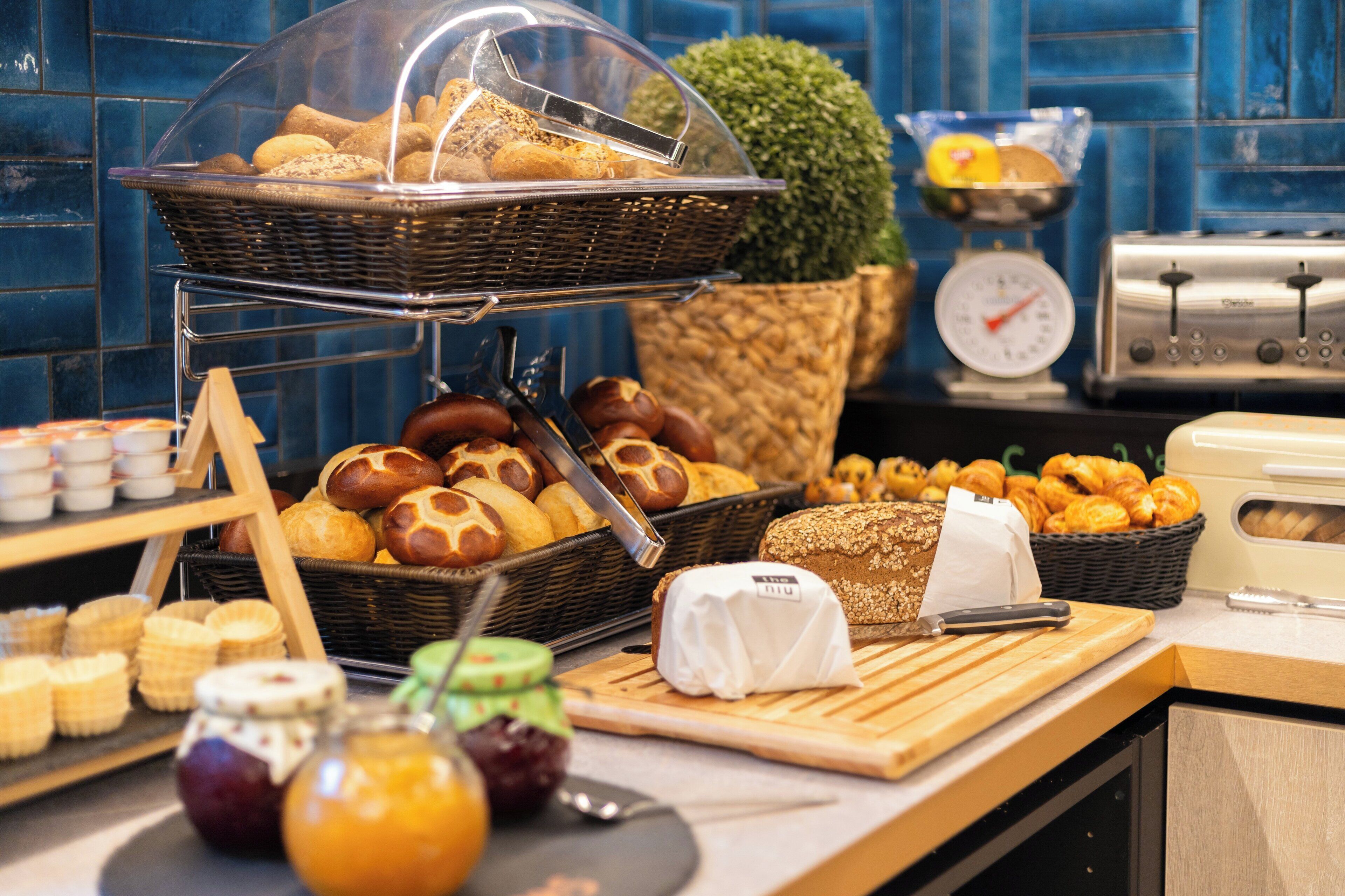 A buffet with various breads, pastries, and cheeses.
