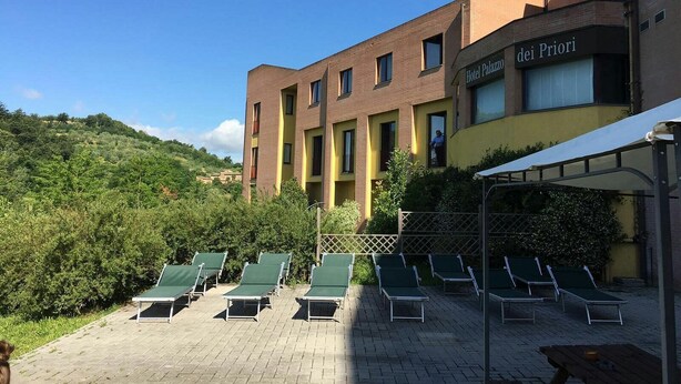 A hotel with a courtyard featuring sun loungers and a covered seating area. - Hotel Palazzo dei Priori (Siena)