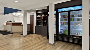 A modern hotel lobby with a reception desk, a vending machine, and a refrigerator stocked with beverages. - Comfort Inn & Suites Fremont (Fremont)