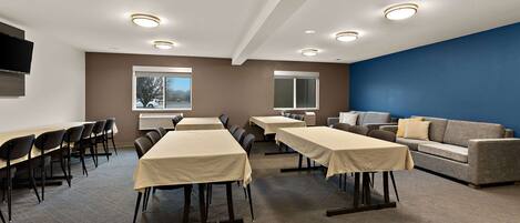 A conference room with tables, chairs, a sofa, and a TV.