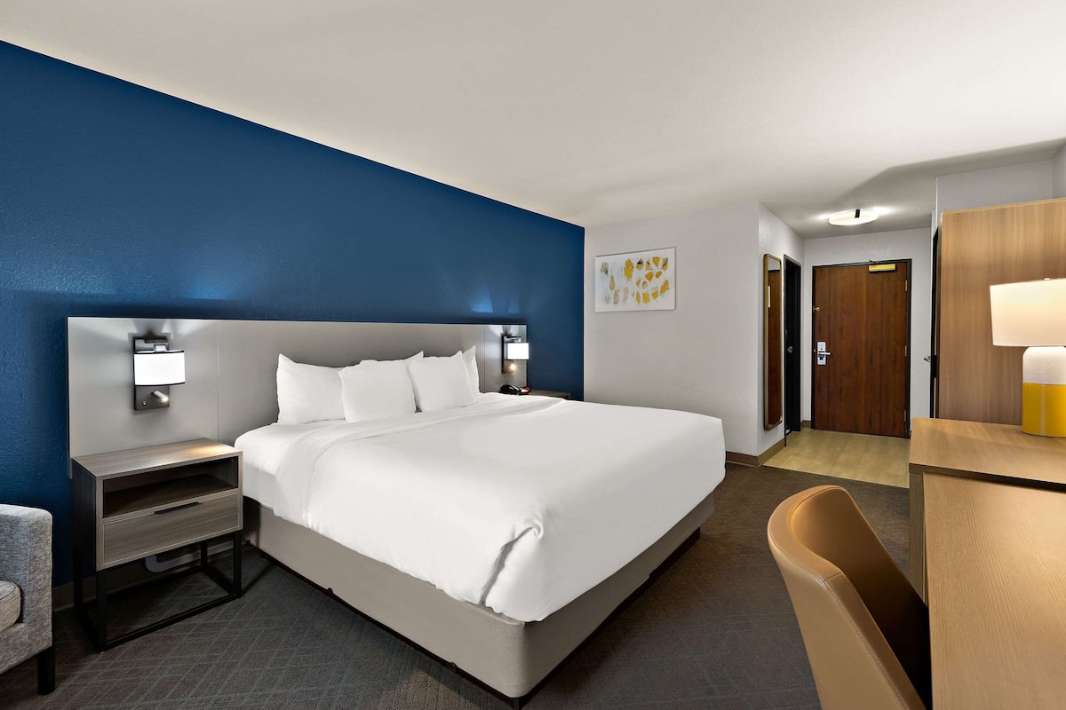 Une chambre d’hôtel avec un grand lit, une table de chevet, un bureau et une chaise.