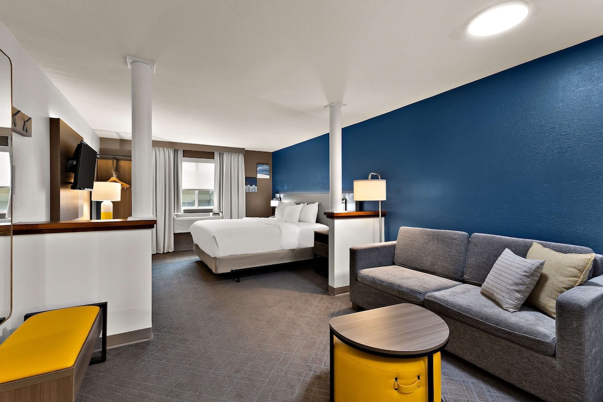 Une chambre d’hôtel avec un lit, un canapé, une petite table et un bureau avec une lampe.