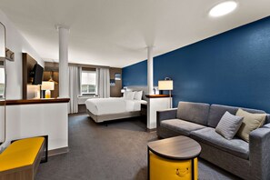 A hotel room with a bed, a sofa, a small table, and a desk with a lamp. - Comfort Inn & Suites Fremont (Fremont)