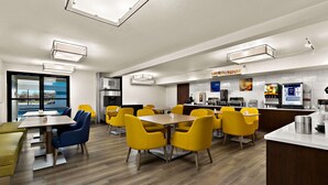 A modern dining area with yellow chairs, a bar, and a kitchen area. - Comfort Inn & Suites Fremont (Fremont)