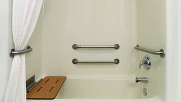 A bathtub with two metal grab bars, a wooden seat, and a shower curtain.