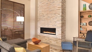 A living room with a stone fireplace, a sofa set, a wooden coffee table, and a bookshelf. - Country Inn & Suites by Radisson, Galena, IL (Galena)