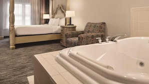 A hotel room with a four-poster bed, a patterned armchair, a large bathtub, and a nightstand with lamps. - Country Inn & Suites by Radisson, Galena, IL (Galena)