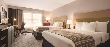 A hotel room with two beds, a desk, a chair, and a window with curtains.