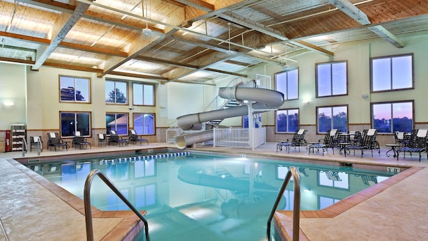 An indoor swimming pool with a water slide, lounge chairs, and large windows. - Country Inn & Suites by Radisson, Galena, IL (Galena)