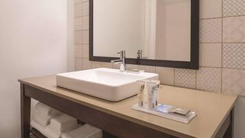 A bathroom with a white sink, a mirror, and a towel rack.
