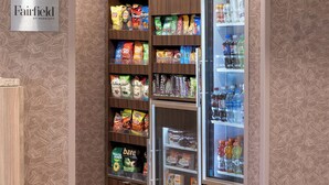 A vending machine stocked with snacks and beverages, located in a hotel setting with a 'Fairfield by Marriott' sign. - Fairfield Inn & Suites by Marriott Cincinnati Eastgate (Cincinnati)