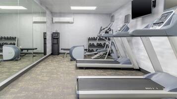 A gym with treadmills, dumbbells, and a water dispenser.