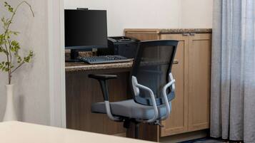 Un espace de travail dans un hôtel, équipé d’un ordinateur, d’un clavier et d’un fauteuil de bureau ergonomique.