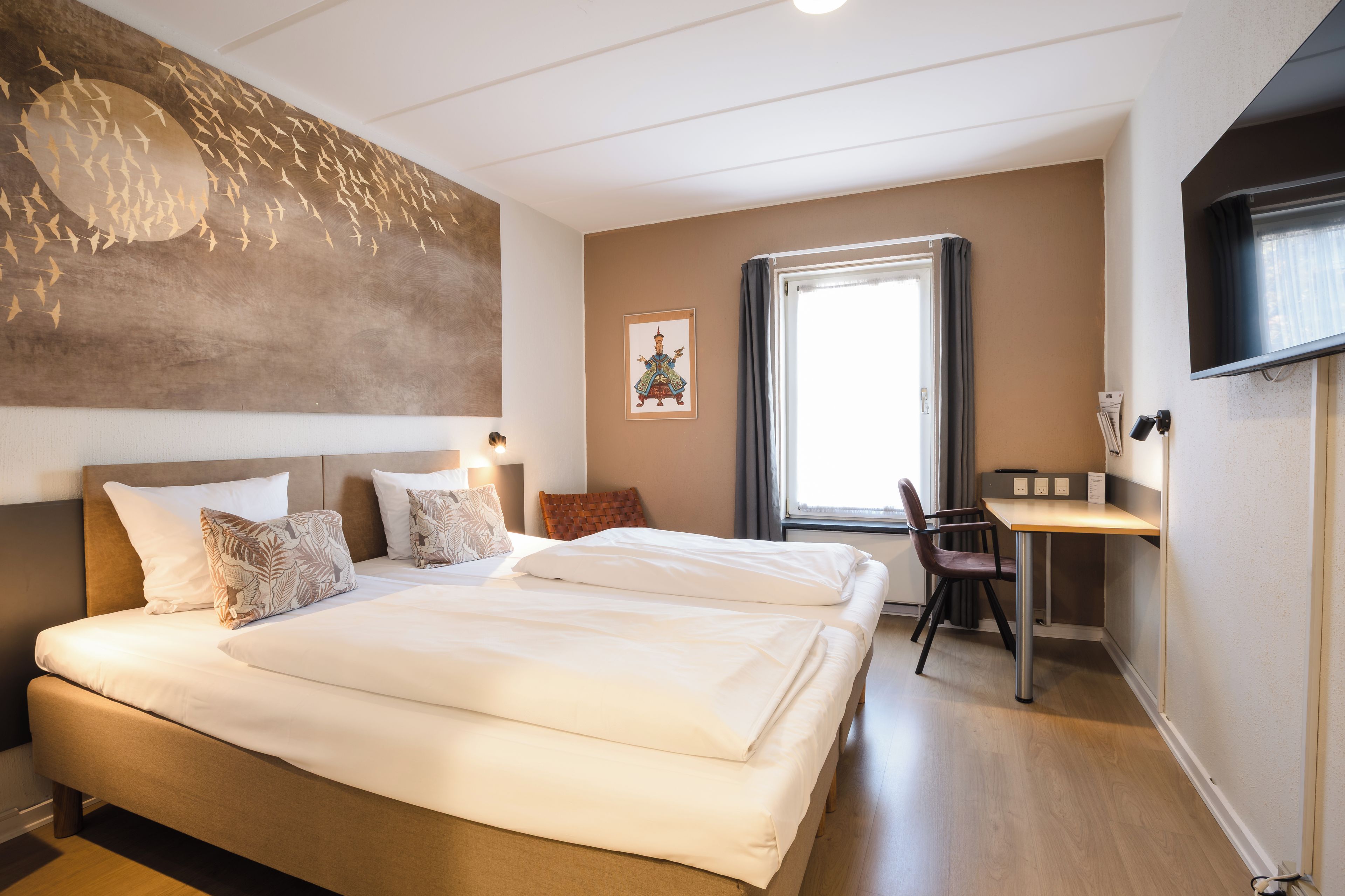 Hotellihuone, jossa on suuri sänky, työpöytä ja televisio.
