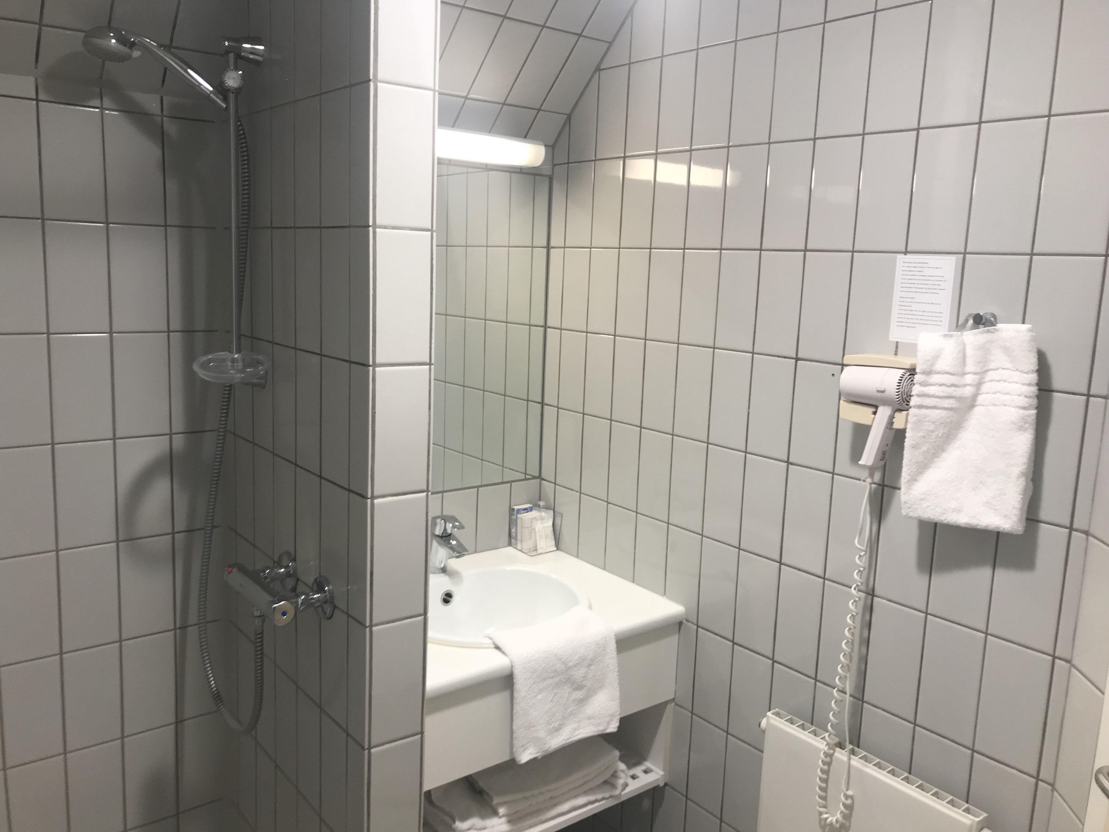 A bathroom with a shower, sink, and towel rack.
