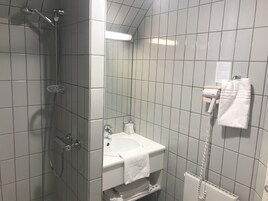 A bathroom with a shower, sink, and towel rack.