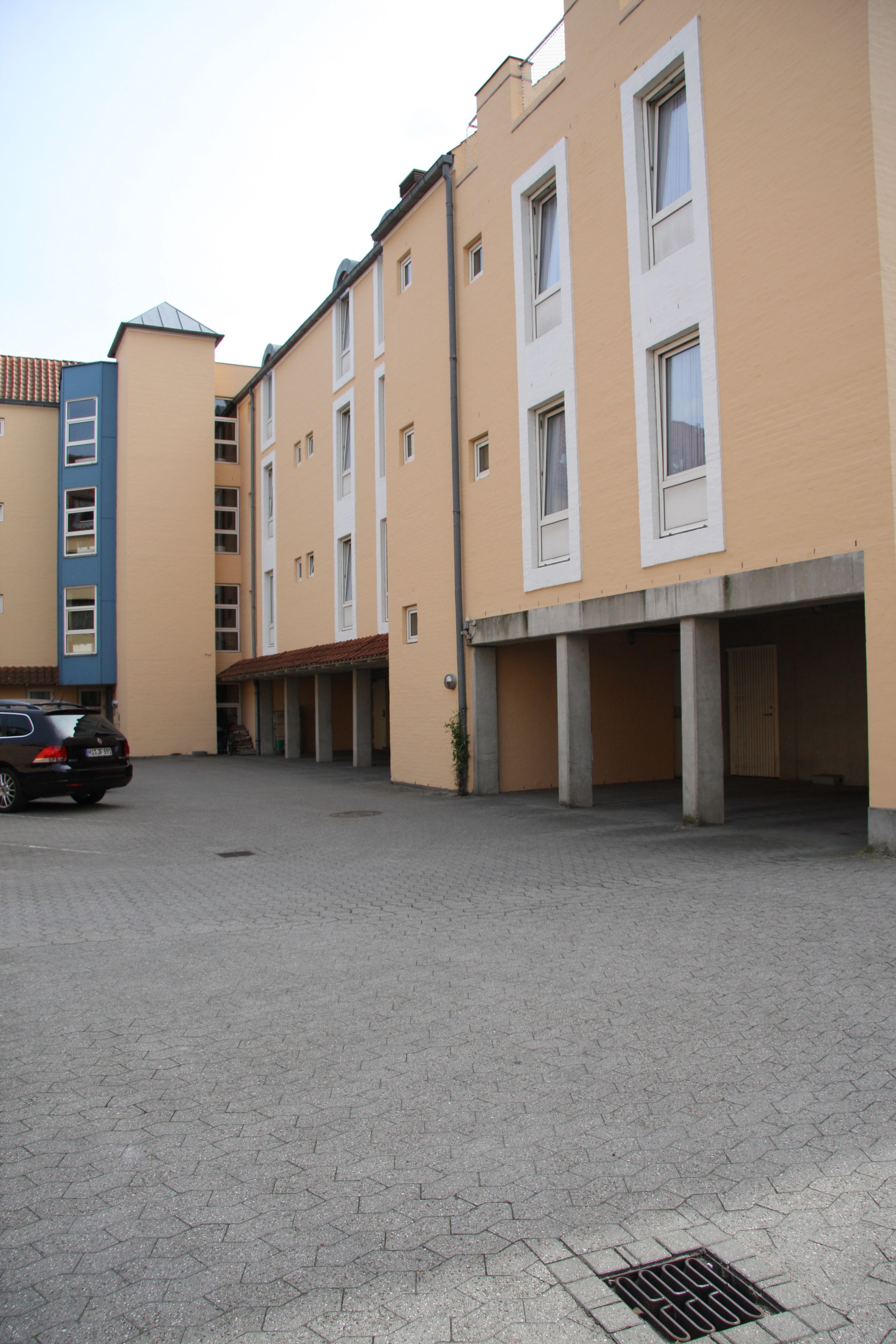 Un edificio residencial de varios pisos con un estacionamiento.