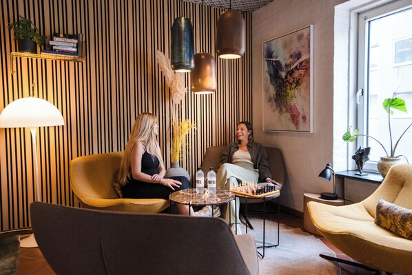 A modern interior with striped walls, a large painting, and a chessboard on a table. - City Hotel Nattergalen (Odense)