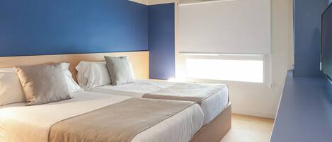 A modern bedroom with two beds, a large window, and a flat-screen TV.