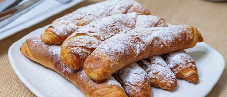 A plate of pastries with powdered sugar, a tiered display of various baked goods, and stacks of white plates.