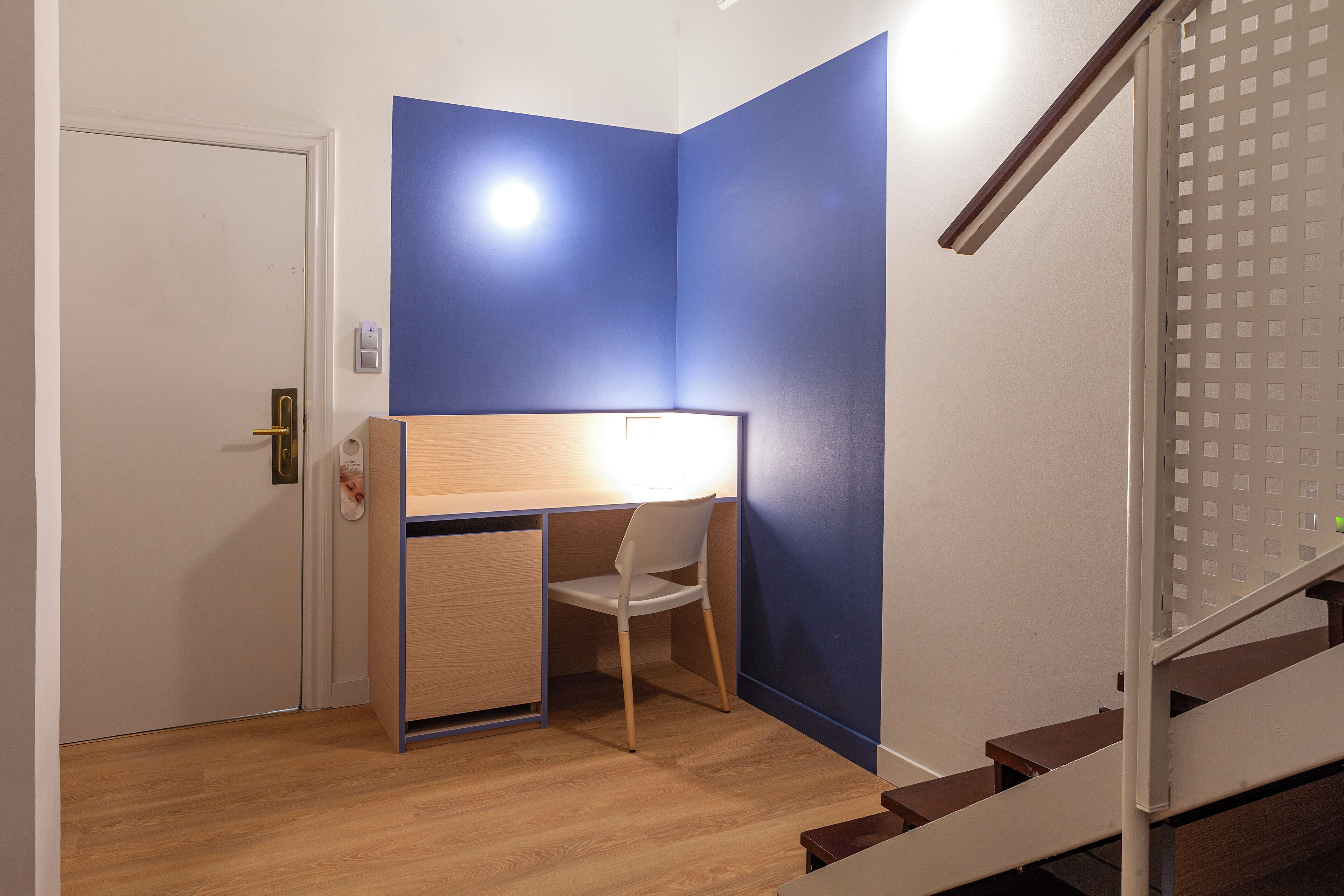 Une pièce de taille modeste, comprenant un bureau, une chaise, une porte et un escalier.